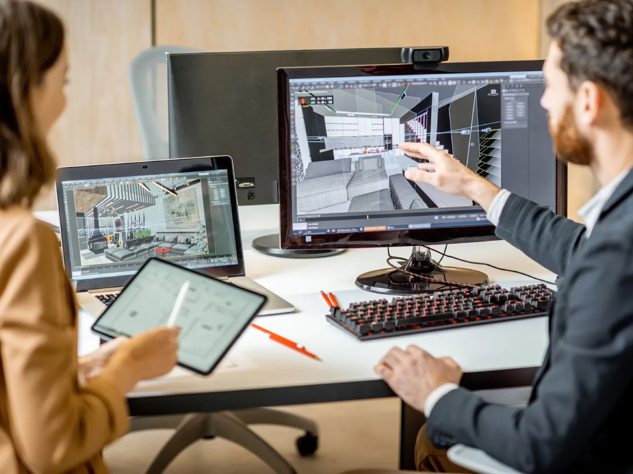 3D visualization specialists reviewing an architectural interior model and rendered scene on multiple screens