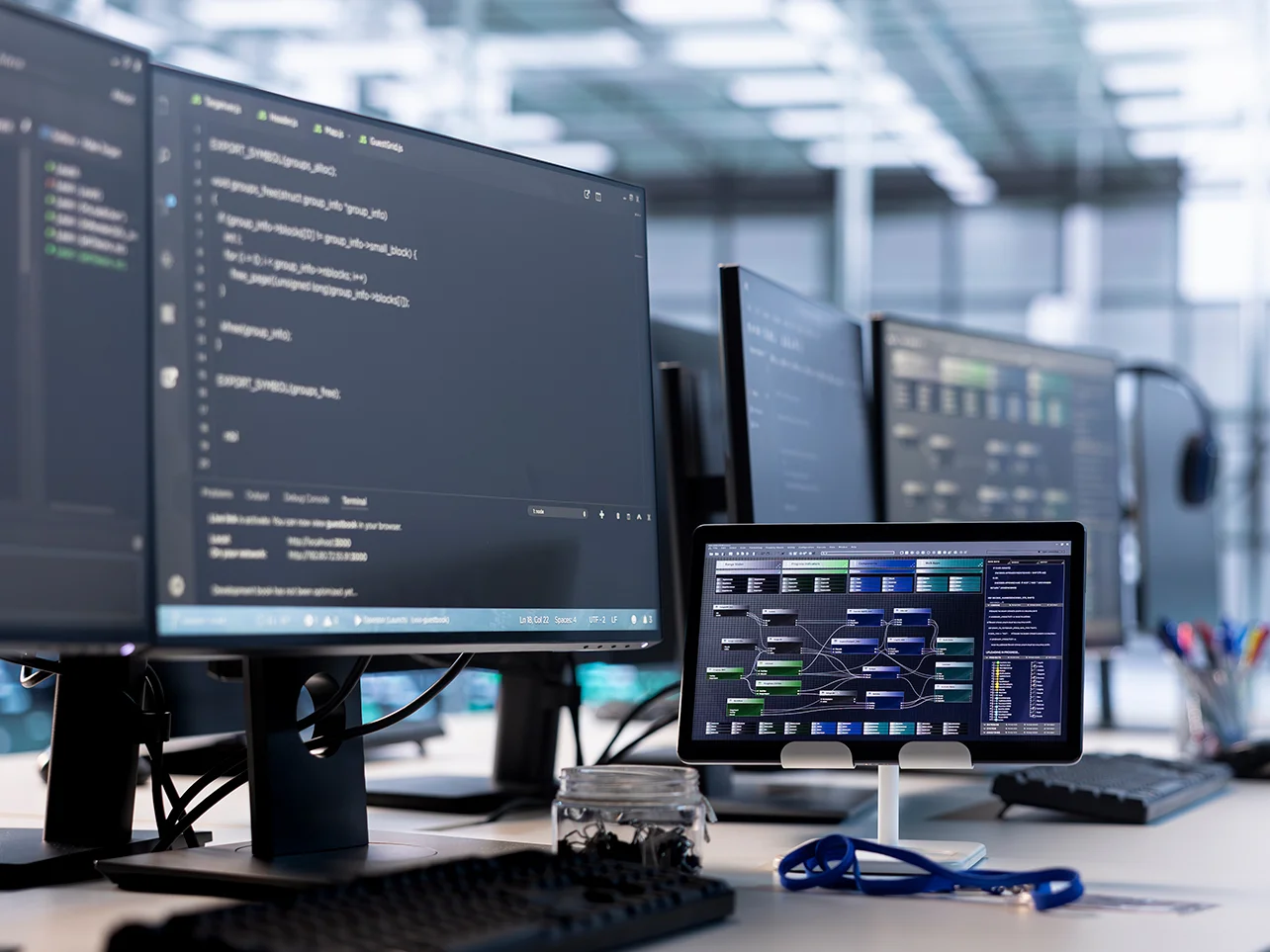 Custom software development workspace with code and system architecture displayed across multiple screens