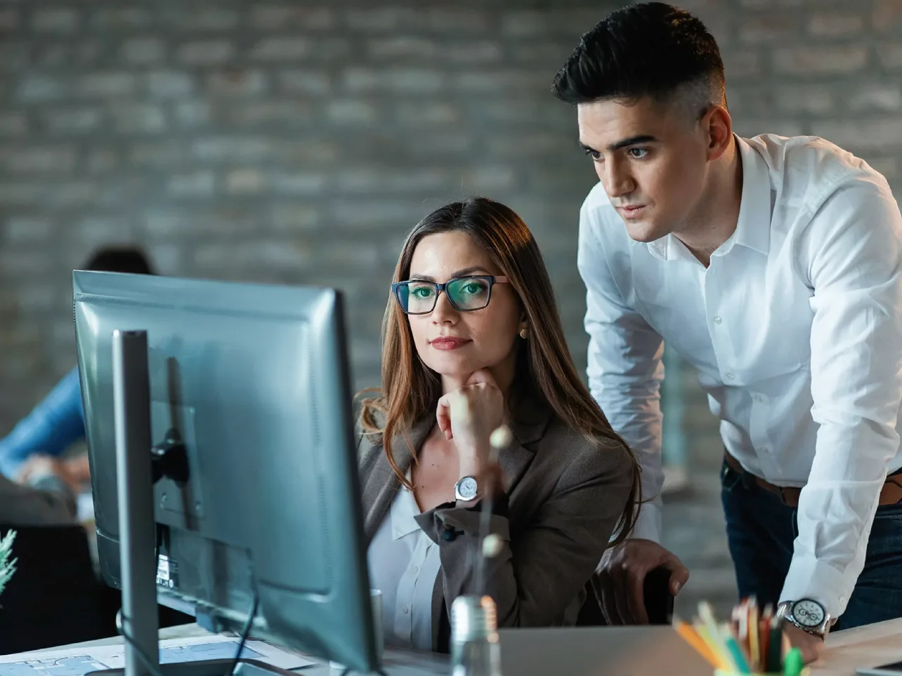 Software development outsourcing specialists collaborating at a computer in a modern office