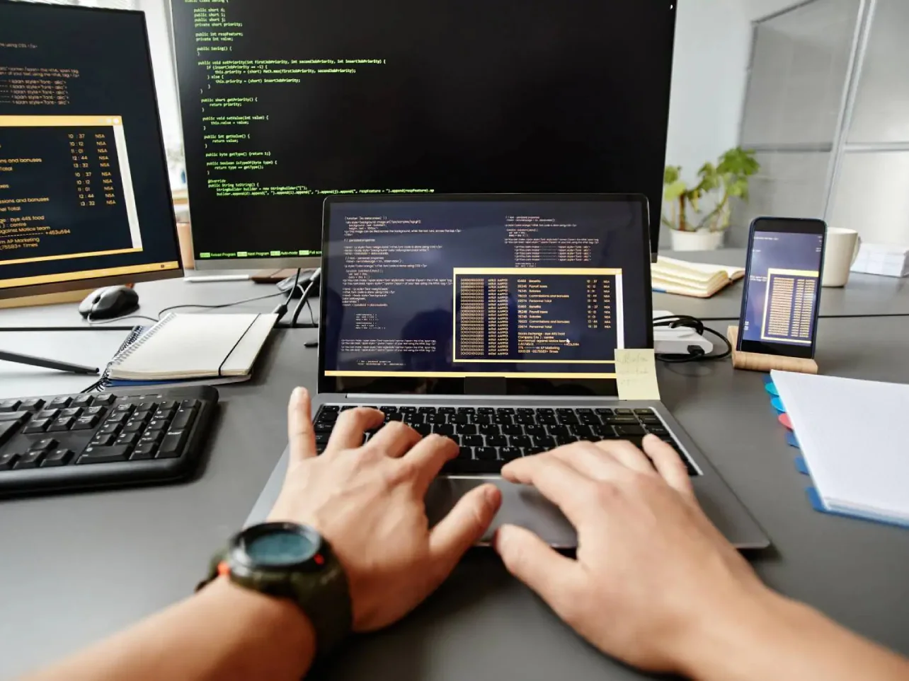 QA engineer testing software across multiple screens and a mobile device