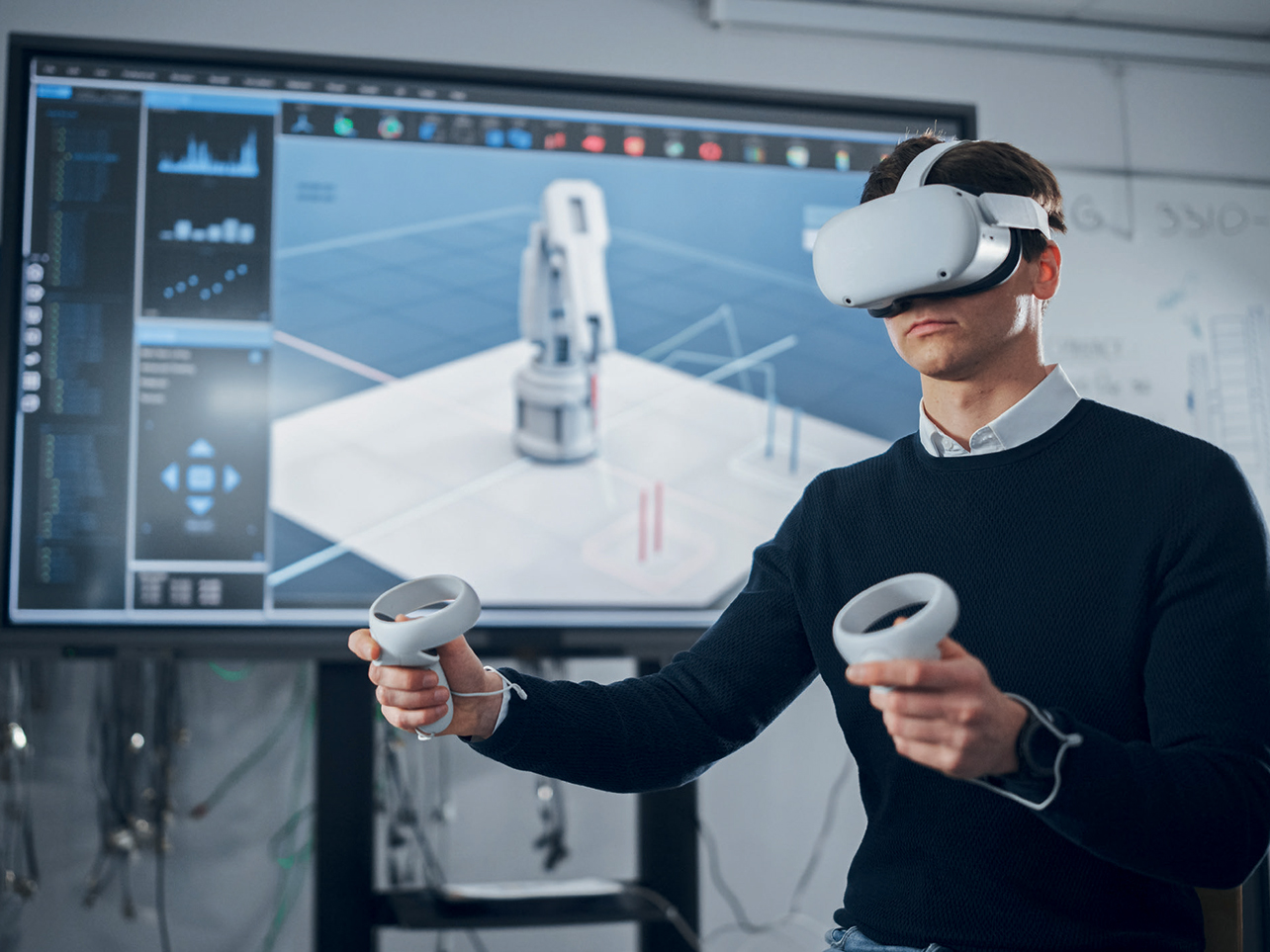 Man using a VR headset and controllers for virtual training and simulation in a lab with a 3D interface on screen